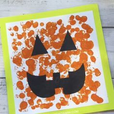 an orange and black paper pumpkin craft on a white wooden table