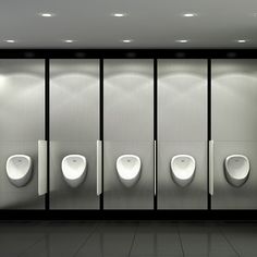 a row of urinals in a bathroom with lights on the ceiling and floor