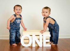 two toddlers standing next to each other in front of the word one