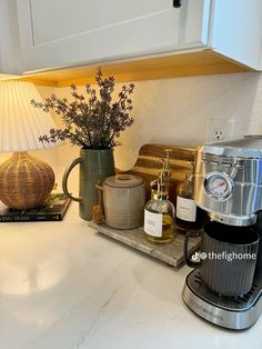 the coffee maker is sitting on the counter next to the mugs and other items