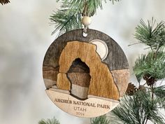 an ornament hanging from a christmas tree with the image of arches national park on it