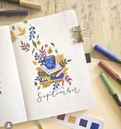 an open notebook with the word autumn written on it next to crayons and markers