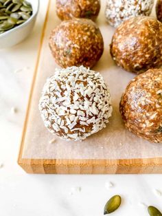 several balls of food sitting on a cutting board next to some seeds and a bowl