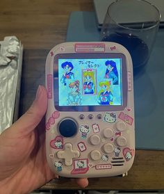 a person holding up a pink toy cell phone with pictures on the screen and buttons