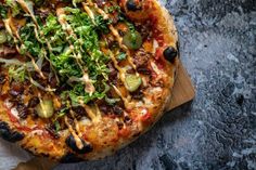 a pizza sitting on top of a cutting board covered in cheese and veggies