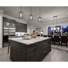 a large kitchen with an island in the middle and two pendant lights hanging from the ceiling