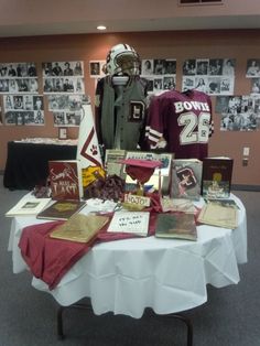 a table topped with football memorabilia and jerseys on display in a room filled with photos