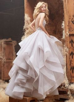 a woman in a white dress standing next to a pile of hay