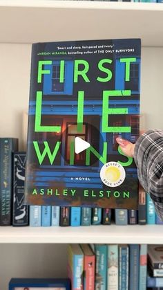 a person holding up a book in front of a bookshelf