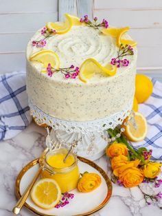 there is a cake with lemons and flowers on the table next to some oranges