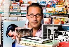 a man holding a cat in front of a pile of books