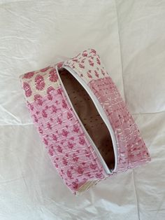 a pink and white purse sitting on top of a bed