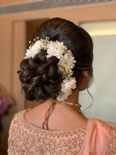 a woman with flowers in her hair is looking at something on the wall behind her