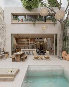 an indoor swimming pool with lounge chairs, tables and potted trees in the background