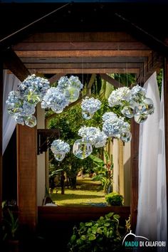 blue and white flowers hanging from the ceiling in front of an open air gazebo