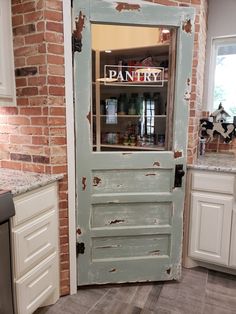 an old door is opened to reveal a pantry in the kitchen with white cabinets and brick walls