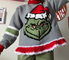 a woman wearing an ugly grin face sweater and matching green pants with her hands in the air