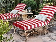 two red and white striped chaise lounge chairs on brick patio with small table in background