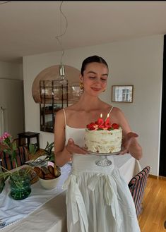 a woman holding a cake with candles on it