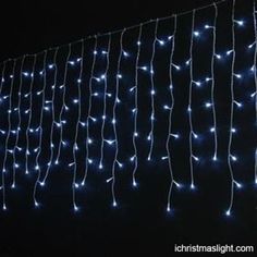 blue christmas lights hanging on a fence at night