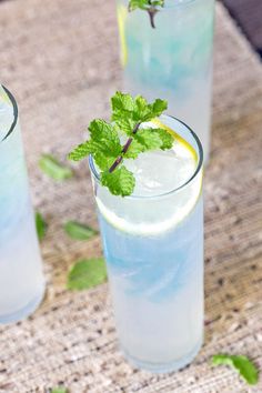 two glasses filled with blue liquid and mint sprigs