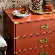 an orange dresser with two drawers and a cup on top