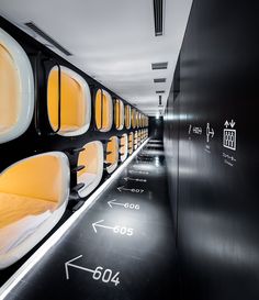 a long hallway with lots of windows and yellow seats on the walls, along with arrows pointing in different directions