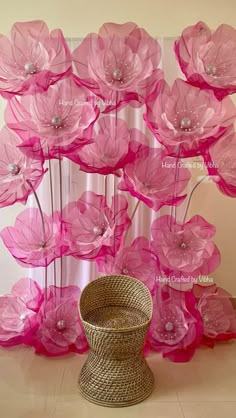 large pink flowers are in front of a curtain with pearls on the top and bottom