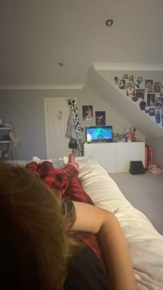 a woman laying on top of a bed in a room with pictures on the wall