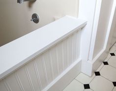 a white bath tub sitting next to a black and white tiled floor