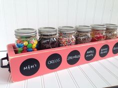 a pink shelf with jars filled with candy and candies on the bottom, labeled mm's