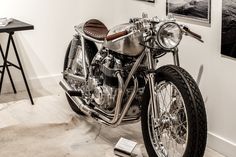 a motorcycle is on display in a room with white walls and wood flooring,