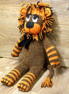 an orange and black stuffed animal sitting on top of a wooden floor next to a wall