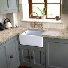 a kitchen with gray cabinets and a white sink in the center, next to a window