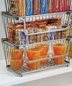 two baskets filled with drinks and snacks on top of a white shelf next to oranges