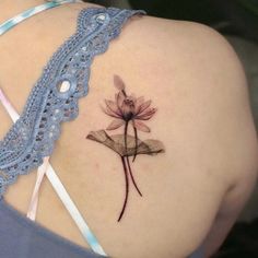 a woman's back with a tattoo on her shoulder and a flower in the center