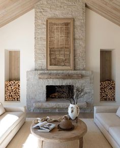 a living room with white couches and a stone fireplace in the middle of it