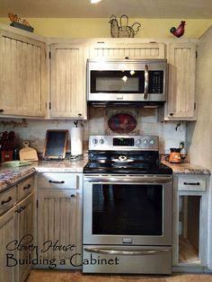 a kitchen with white cabinets and stainless steel stove top oven in the middle of it