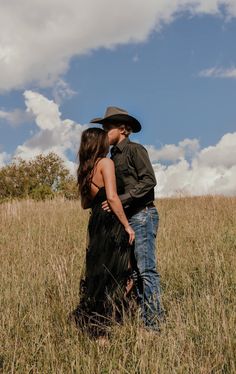 a man and woman are standing in the tall grass with their backs to each other