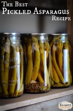 three jars filled with pickled asparagus sitting on top of a shelf