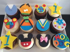 cupcakes decorated with mickey mouse and other birthday related items are displayed in a box