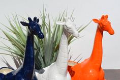 three ceramic giraffes sitting next to each other on top of a table