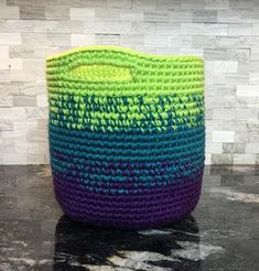 a green and blue basket sitting on top of a counter next to a white wall