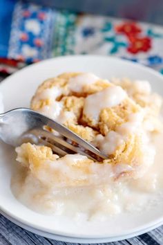 a white plate topped with a piece of cake covered in icing and a fork