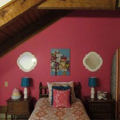 a bedroom with pink walls and two lamps on either side of the bed, in an attic