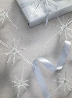 a gift wrapped in white paper with silver ribbon and snowflakes