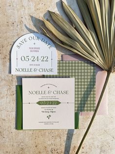 the wedding stationery is laid out on top of each other, including a palm leaf