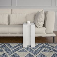 a white couch sitting on top of a wooden floor next to a blue and white rug