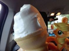 an ice cream sundae in the back seat of a car with a pony figure next to it