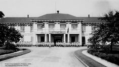 an old black and white photo of people in front of a building with flags on it